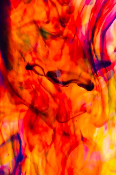 Abstract blur focus vibrant colors flowing with colored inks dispersed in water. The composition consists of shades of blue, red, green and yellow blending and swirling on a light background, creating