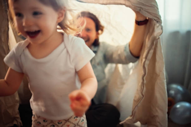 Joyful moment of a child enjoying playful interaction with a parent, set in a warm and welcoming indoor atmosphere. Perfect representation of family happiness and bonding in a cheerful and loving ambiance. Out of focus.