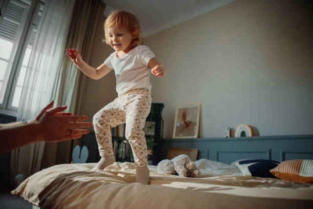 istock Happy Child Playing on a Bed in a Bright Modern Bedroom 2203239162