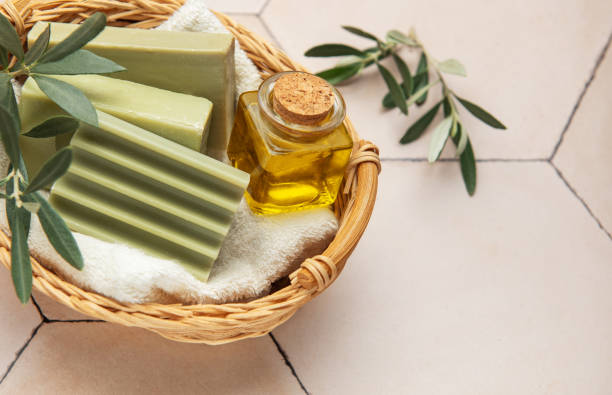 istock Olive soap bars, olive oil and branches resting in wicker basket on beige tile 2203240012