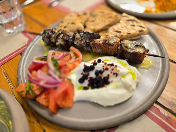 istock Delicious grilled kebab served with fresh salad and flatbread on a rustic wooden table 2203240198
