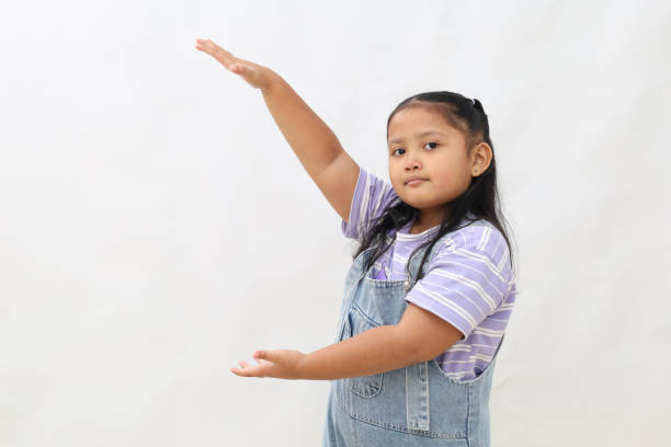 Happiness expression of asian little girl while presenting something on empty space.