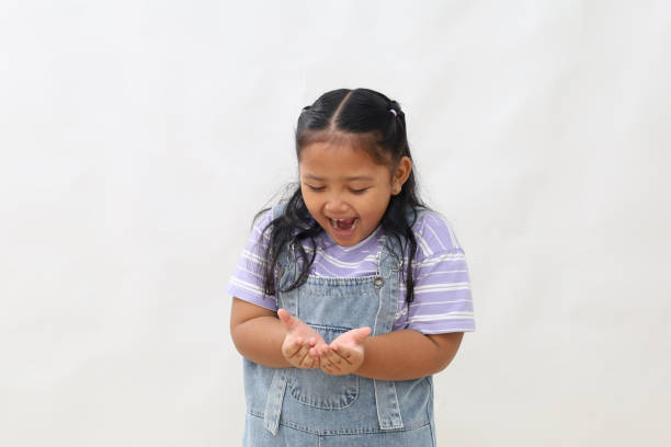 istock Wow and amazed expression of asian little girl while holding something on her hands 2203242311