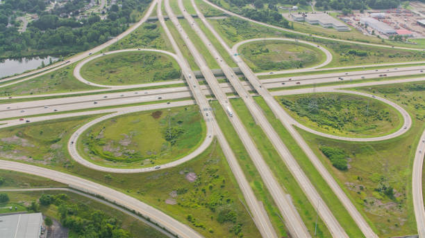 Aerial perspective of a cloverleaf interchange in Lansing, Michigan, surrounded by lush greenery, showcasing intricate roadway patterns and urban planning.