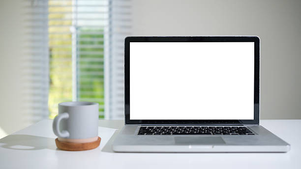 istock Modern home office setup featuring a blank laptop screen and a gray coffee cup, perfect for presentations or mockups. 2203250275