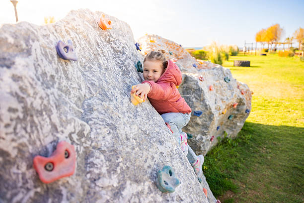 istock Little girl climbing an artificial climbing wall in a playground, developing strength and coordination 2203252115