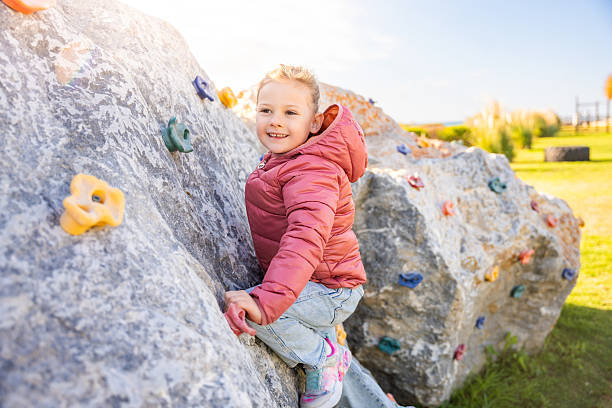 istock Little girl climbing an artificial climbing wall in a playground, developing strength and coordination 2203252126