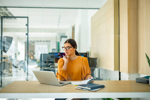 istock Young woman engaged in thoughtful planning at a modern office workspace with technology and collaboration 2203252818