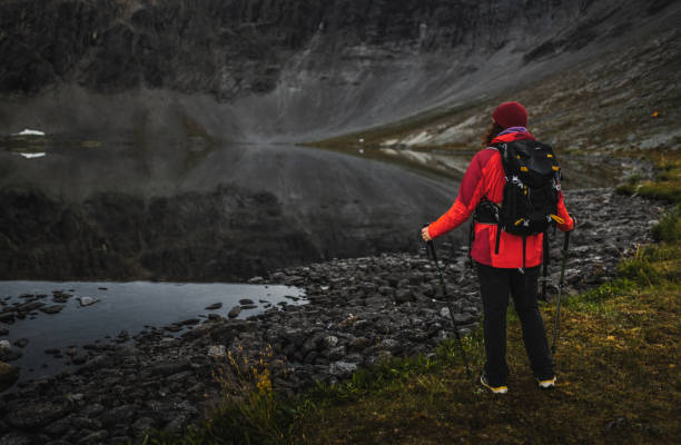 istock Hiker standing by a reflective lake in a serene mountain landscape 2203254368
