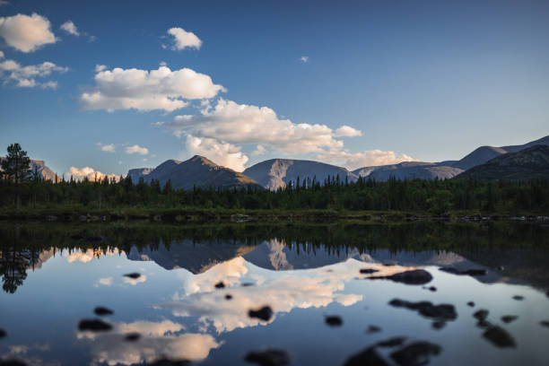 istock Serene lake reflecting mountains and clouds under a bright blue sky 2203254406