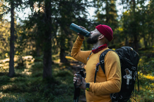 istock Man Enjoying Hydration While Hiking Through a Scenic Forest Trail 2203254480
