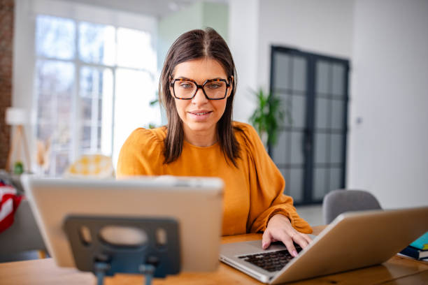istock Young woman enjoys working from home in a cozy apartment while multitasking on digital devices 2203255956