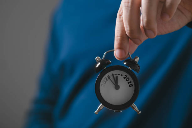 istock Person holding a small classic alarm clock, symbolizing time management and punctuality. Focus on clock face with blurred background. 2203258174