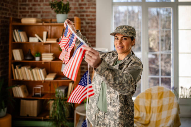 istock Young woman in military uniform decorates home with flags while preparing for a celebration 2203258256