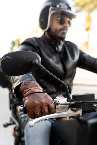 istock Biker wearing leather gloves and helmet riding motorcycle 2203259578