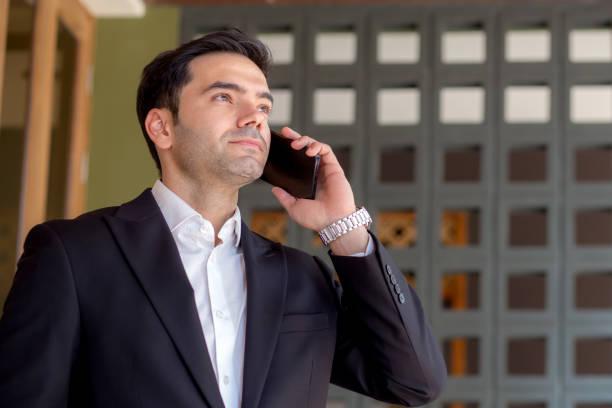 Portrait caucasian businessman standing and talking on smart phone with confident expression outside building, business man speaking on smartphone with expression, business and communication.