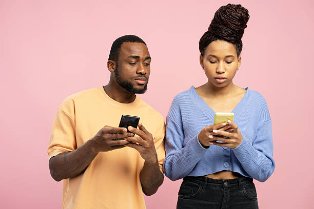 istock Curious man peeking at woman's phone on pink background 2203262402
