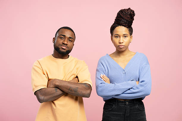 istock Serious young couple crossing arms with offended expression on pink background 2203262465