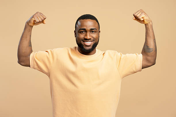 istock Strong young man flexing muscles and smiling on beige background 2203262974