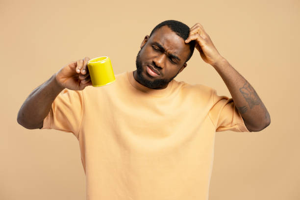 istock Puzzled young man scratching his head while holding a cup of coffee 2203263658