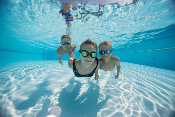 istock Three cute kids swimming underwater in a pool 2203267081