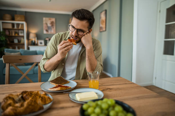 istock Depressed man eating breakfast alone at home 2203267318