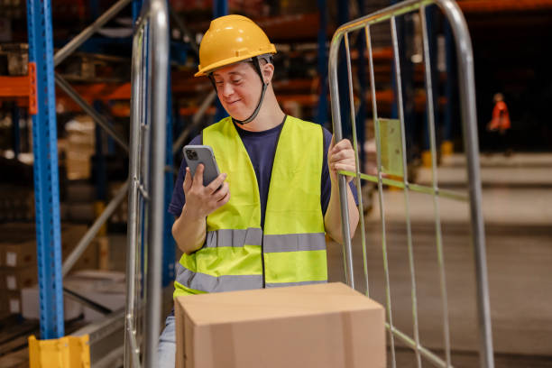 istock Warehouse worker with down syndrome using smartphone and pushing cart 2203268341