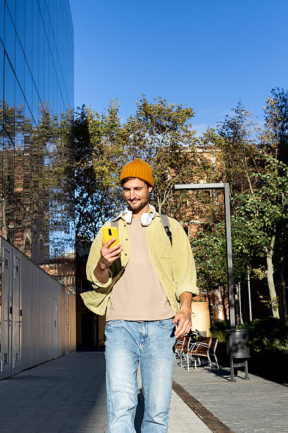 istock Young man walking and using smartphone in the city 2203269629