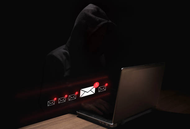 istock Hacker in dark hoodie sending phishing emails to a laptop user 2203271767