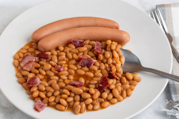 two hot dogs  served with beans and bacon,