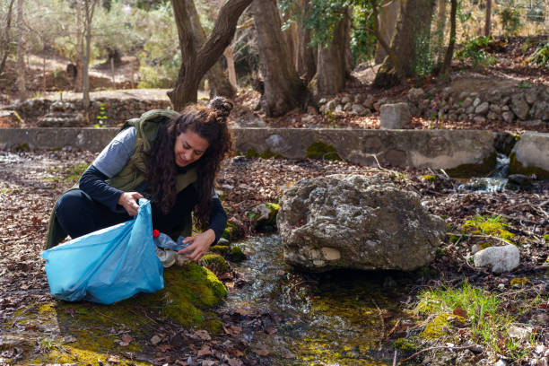 Volunteer collecting plastic bottle in a stream in the forest