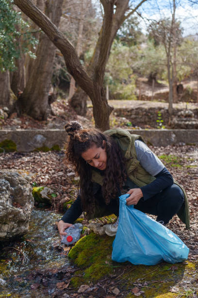 istock Woman collecting plastic bottle from a stream in the forest 2203273996