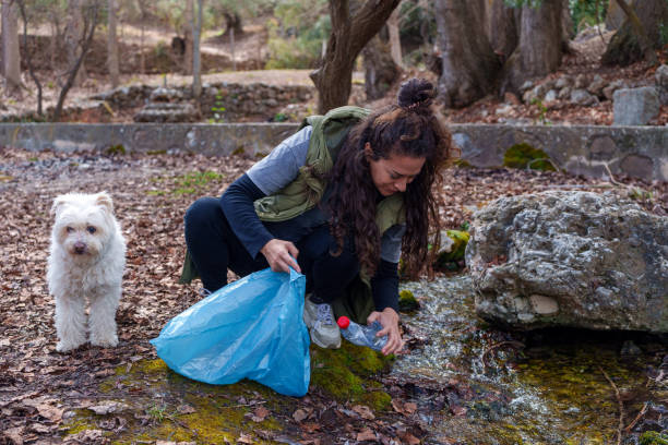 istock Volunteer collecting plastic bottle in forest with her dog 2203274024