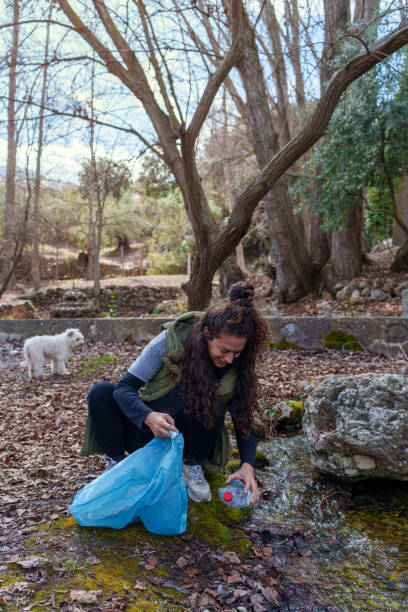 istock Woman collecting plastic bottle in forest with her dog 2203274067