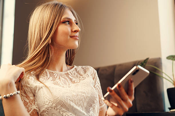 istock Happy young woman using her smartphone while sitting in cafeteria 2203275318