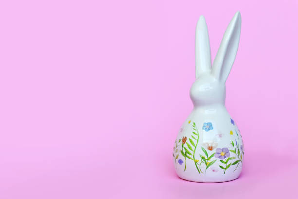 White Easter bunny home decor figurine painted with spring flowers on pastel pink background