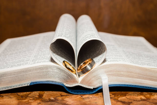 Holy bible with wooden cross, flowers and candles on white satin