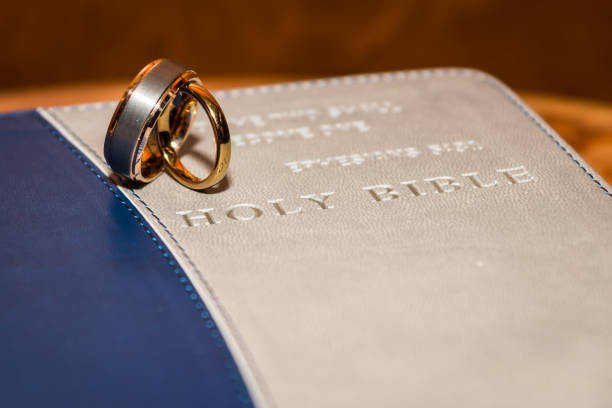 A pair of wedding bands standing on top of a Holy Bible cover.