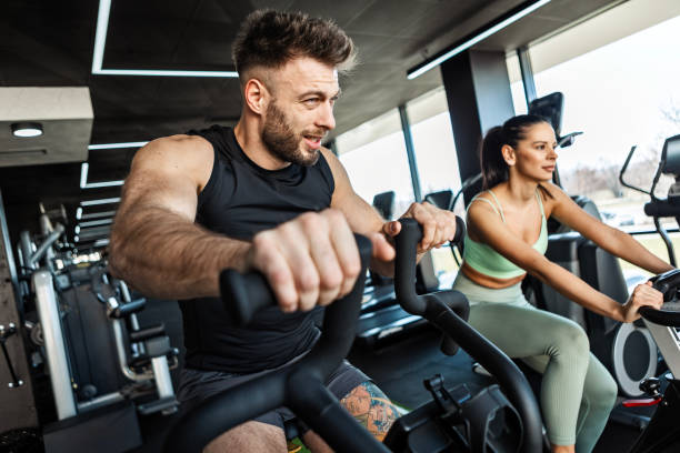 istock Gym Couple Cycling Together on Exercise Bikes 2203280942