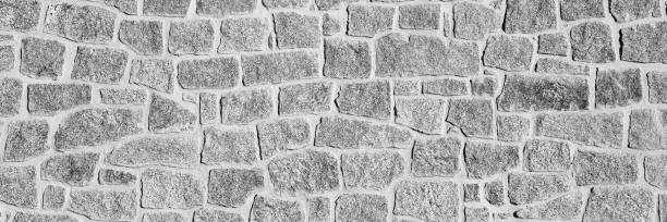 istock Black and white close-up of an irregular stone wall. The rough texture and natural patterns create a rustic and historical appearance. Ideal for backgrounds, textures. Long banner 2203281469