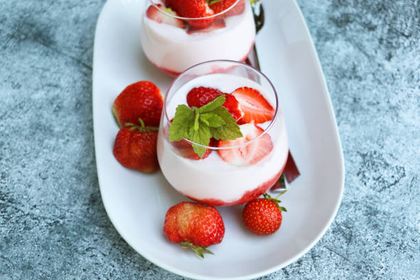 istock Red strawberries with whipped cream dessert on blue background 2203287076