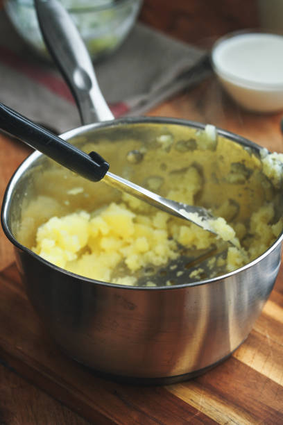 Mashed potatoes with butter and fresh white potatoes on background, wooden table. Healthy food.