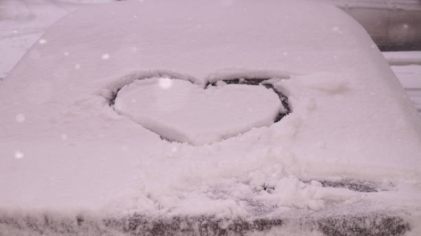 istock car covered with snow and heart drawing on it 2203287577