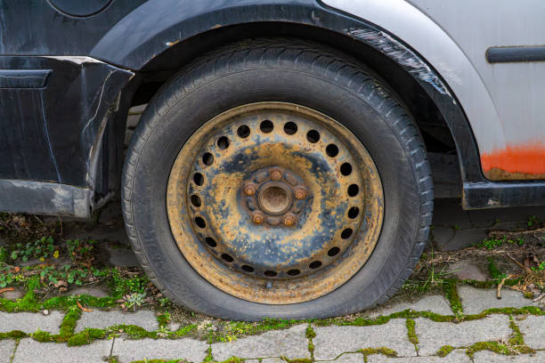 multi-colored paints on a car. car sheet metal elements covered with rust. cheap car repair after a collision. botched bodywork and paint job. abandoned car. flat tire