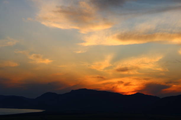 a cloudy sunset and a mountain in darkness.