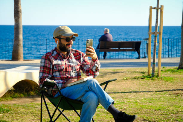 istock Cheerful man making a video call on the beach 2203291312