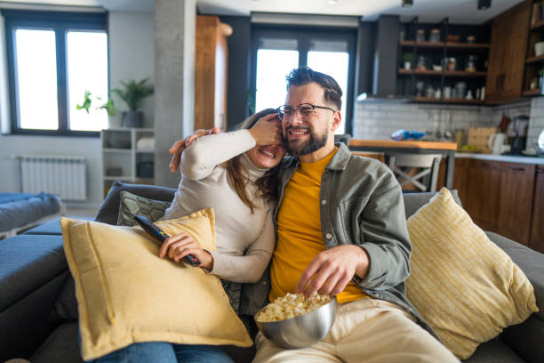 istock Playful couple watching tv and having fun at home 2203292111