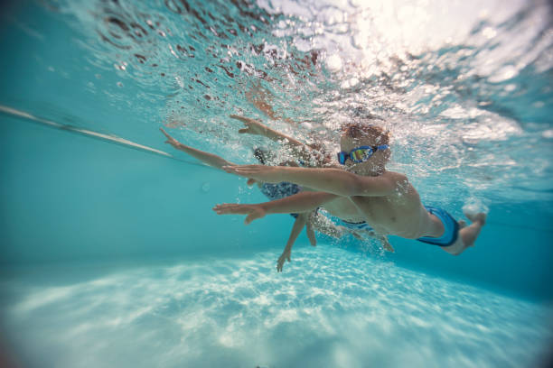 istock Three cute kids swimming underwater in a pool 2203296859