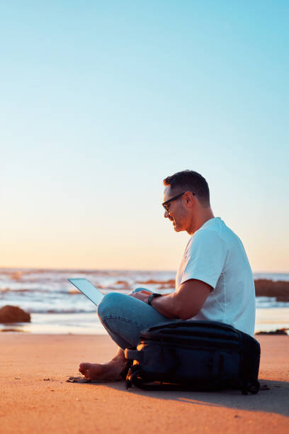 istock Digital nomad working remotely on the beach at sunset 2203297702
