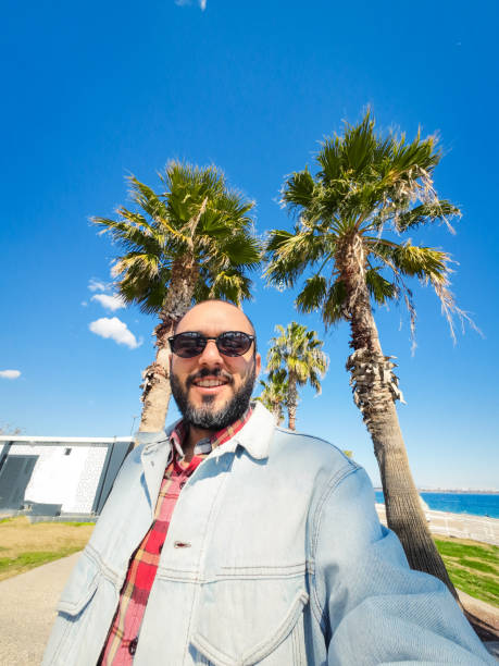 istock Young man in denim jacket walking along the seaside promenade 2203298941